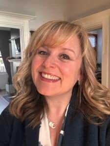 Beverley Nolker, a head and shoulders photo. Beverley is blond haired and smiling at the camera